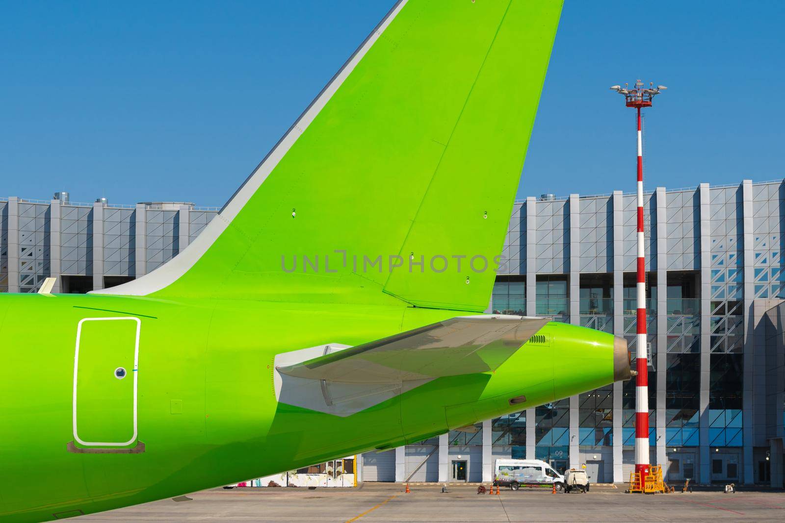 Green passenger airplane at the airport on sunny day by Fabrikasimf