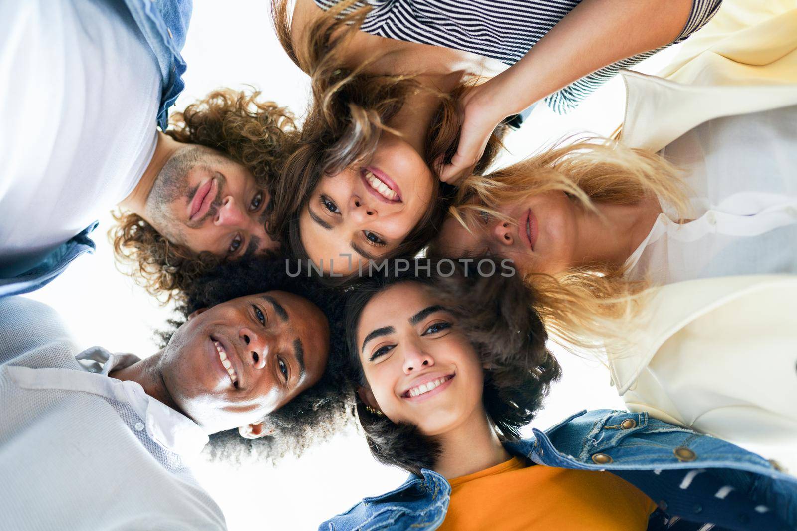 Multi-ethnic group of friends with their heads together in a circle outdoors