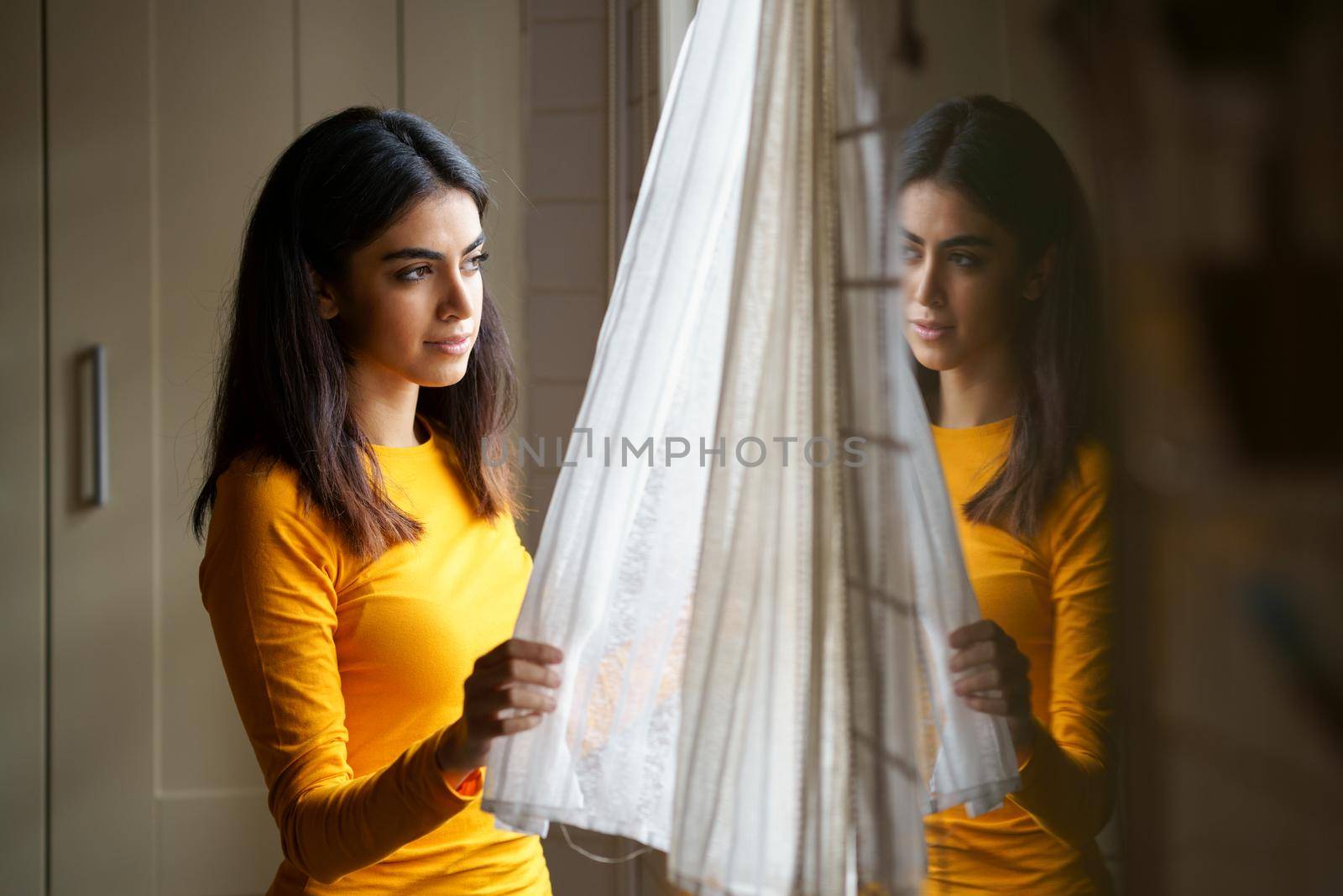 Persian woman at home while looking through the window