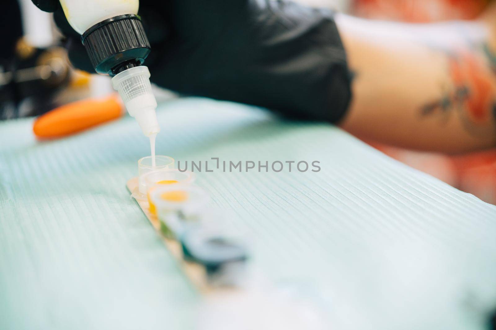 Female tattooist preparing the dyes she's going to work with using white ink. Tattoo concept.