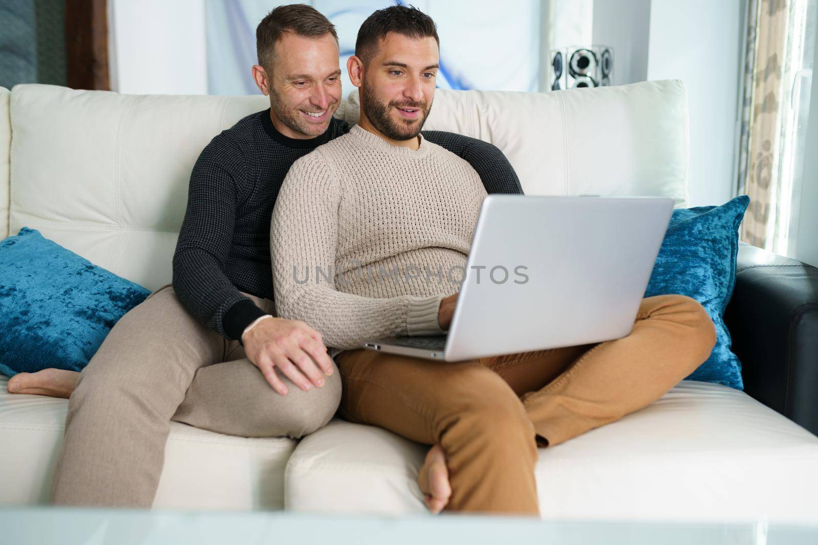 Gay couple consulting their travel plans together with a laptop. Homosexual Lifestyle concept.
