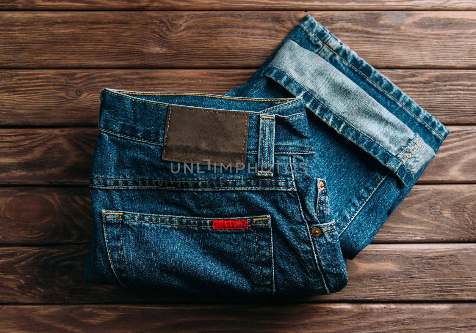 Blue jeans denim pants on a wooden background, top view.
