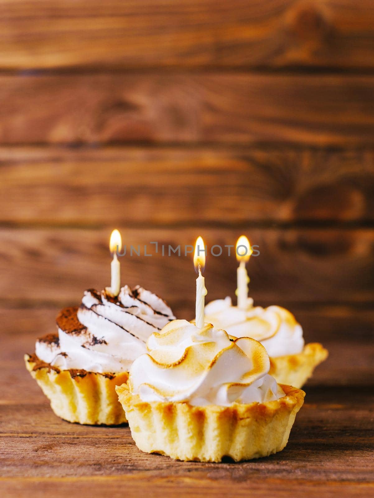Birthday delicious cream cupcakes with candles on a wooden table.