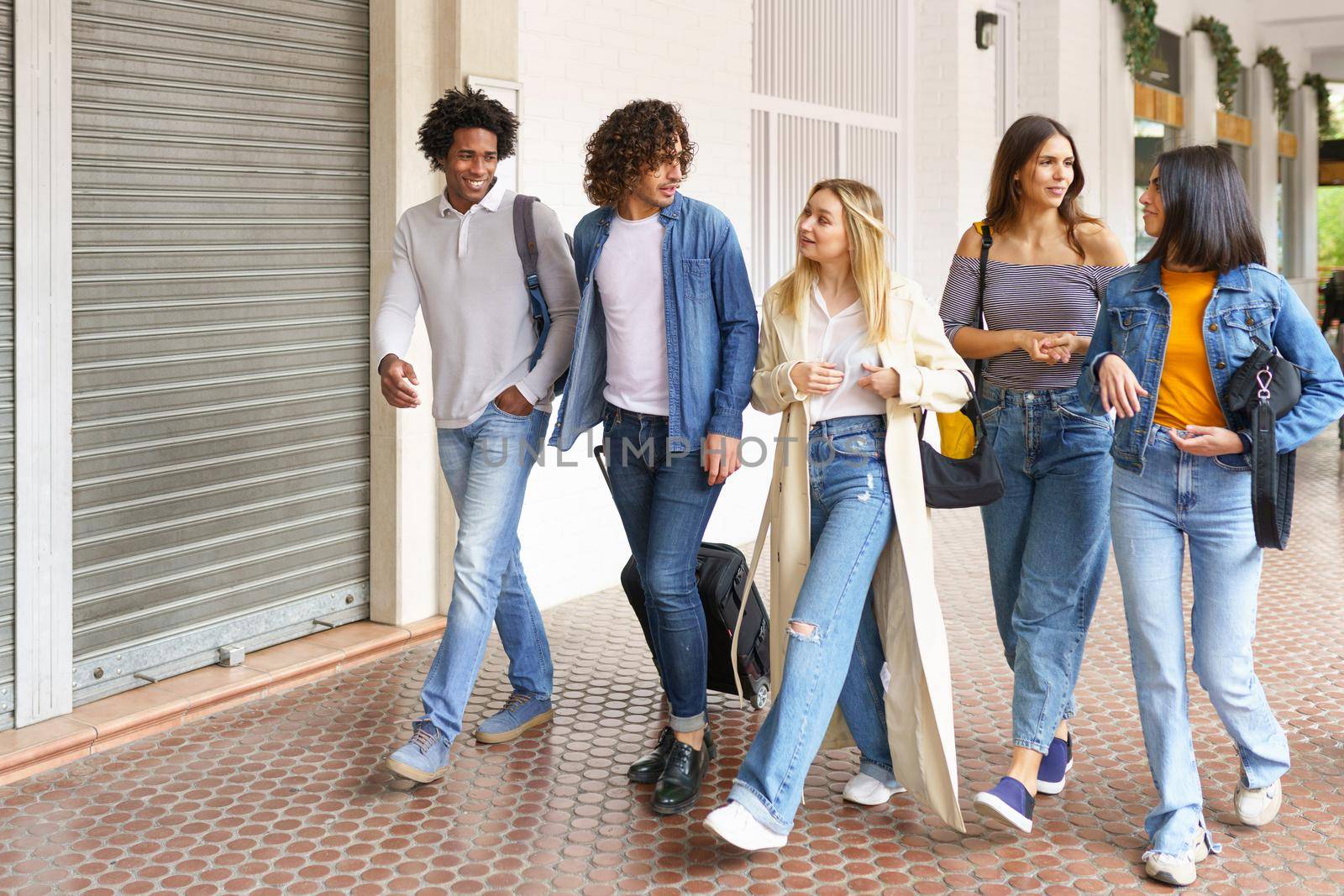 Multi-ethnic group of friends walking together on the street while chatting and having fun.