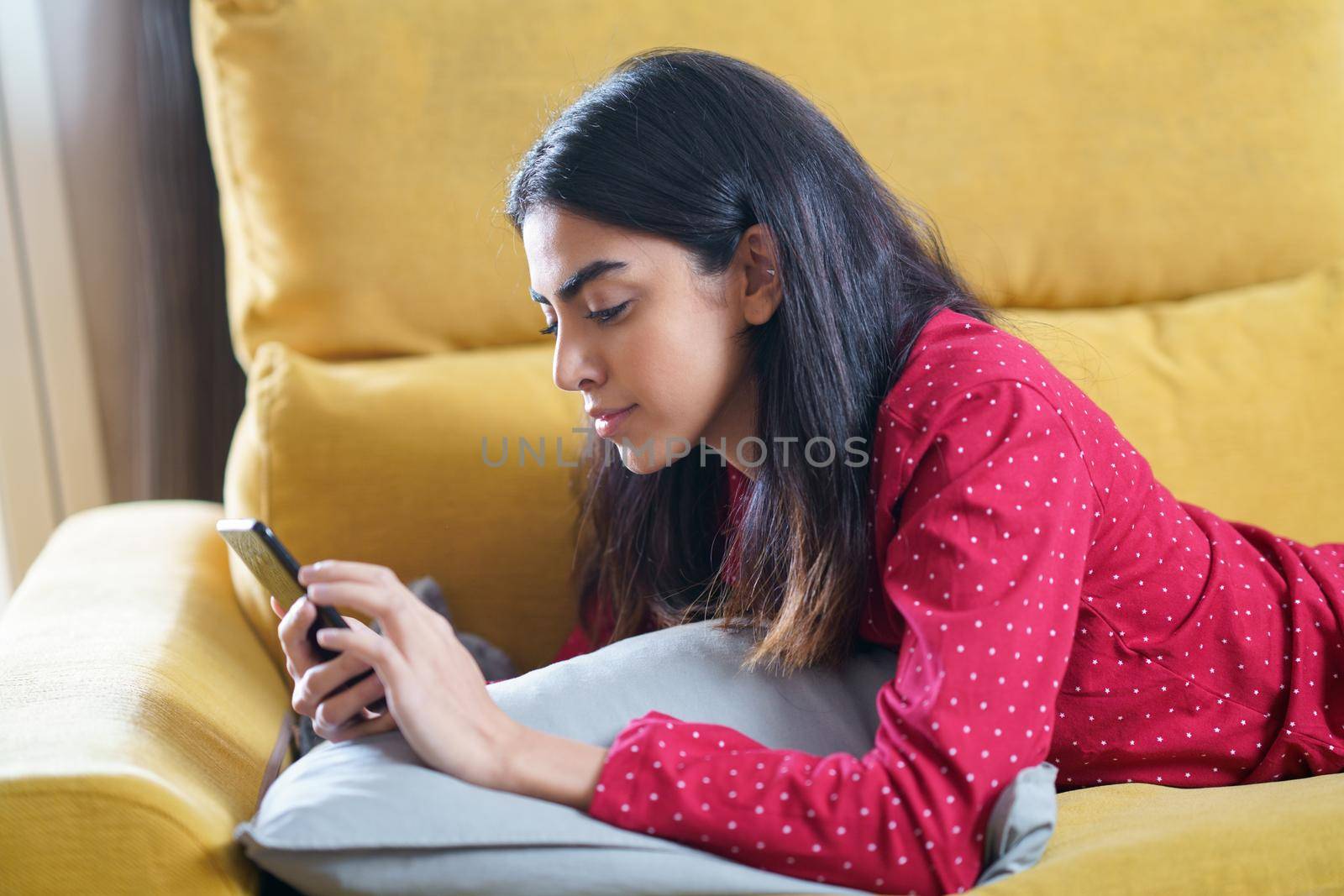 Persian woman at home using smartphone on a couch