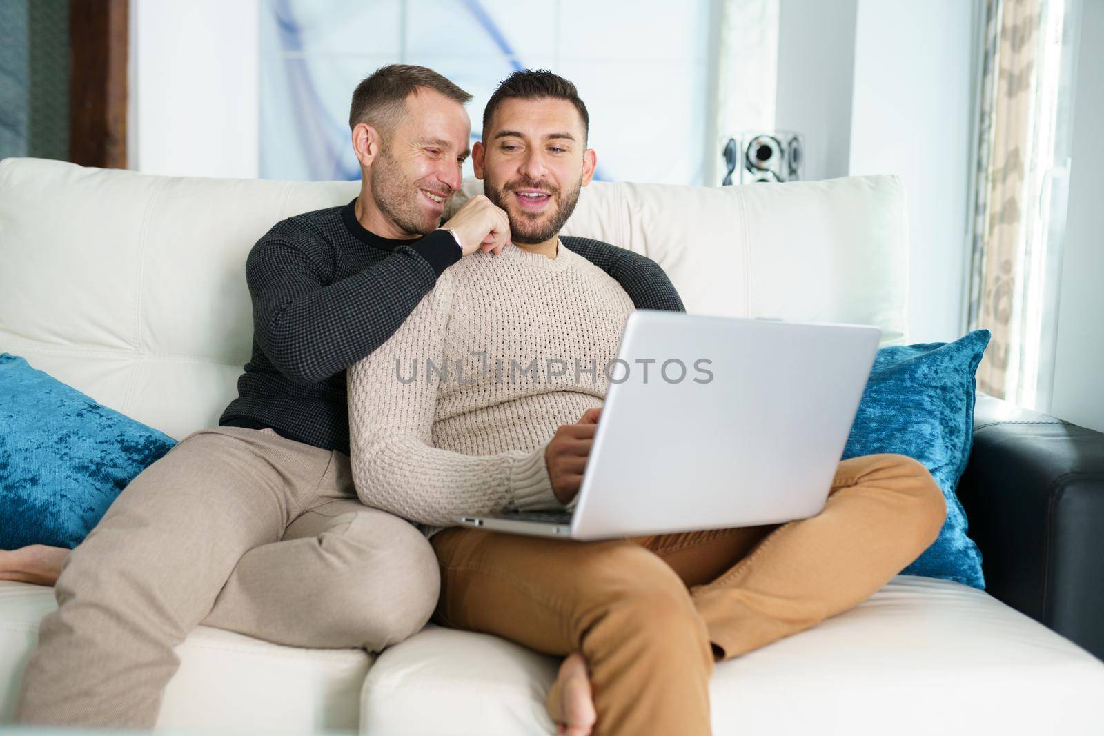 Gay couple consulting their travel plans together with a laptop. Homosexual Lifestyle concept.
