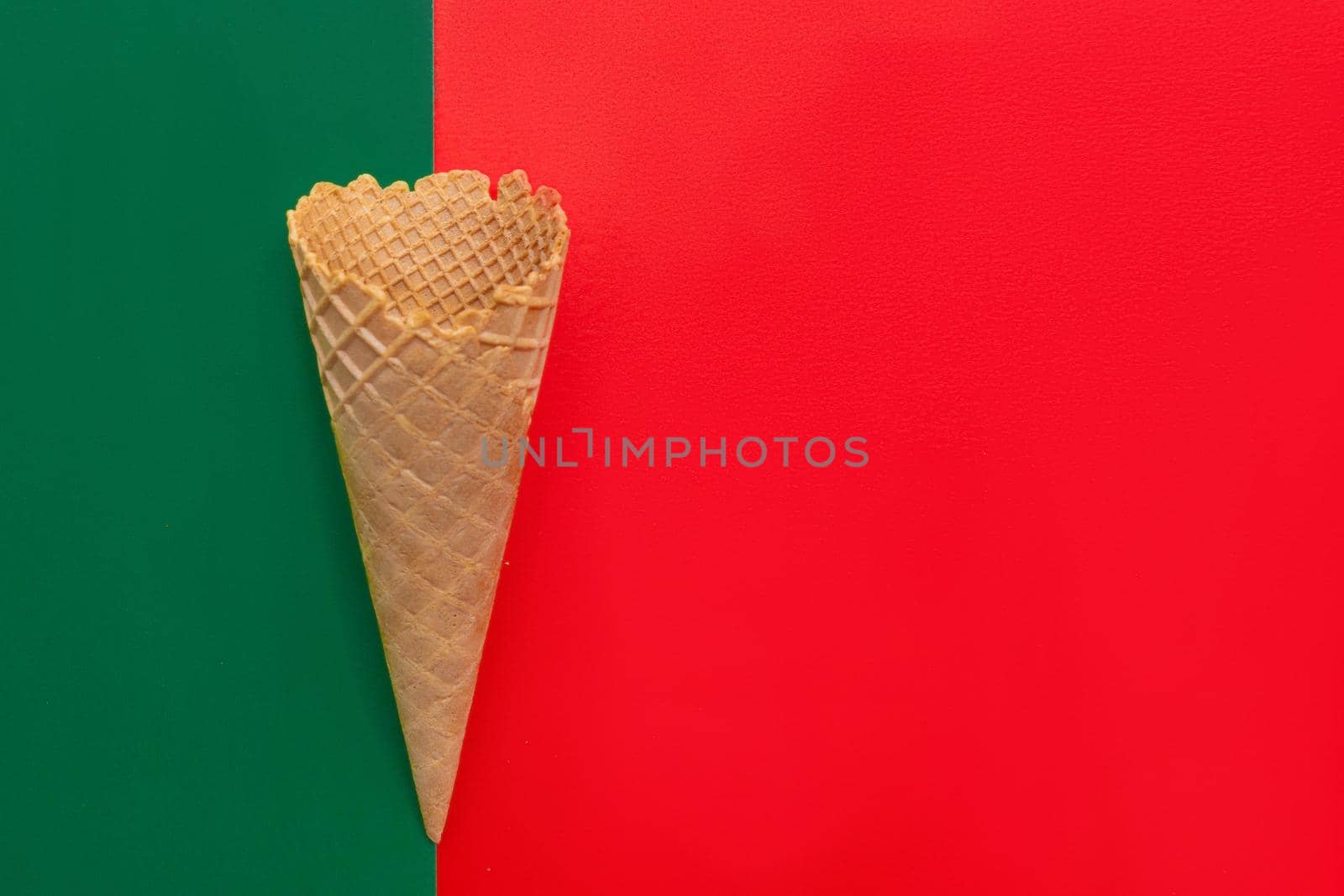 Top view at the empty waffle cone on red and green background, special concept, enough place for text, diagonal position