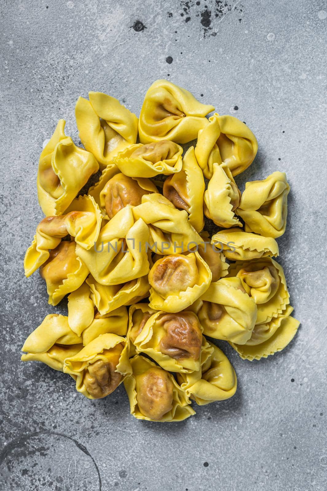 Uncooked raw ravioli with Mozzarella and Tomato. Gray background. Top view.