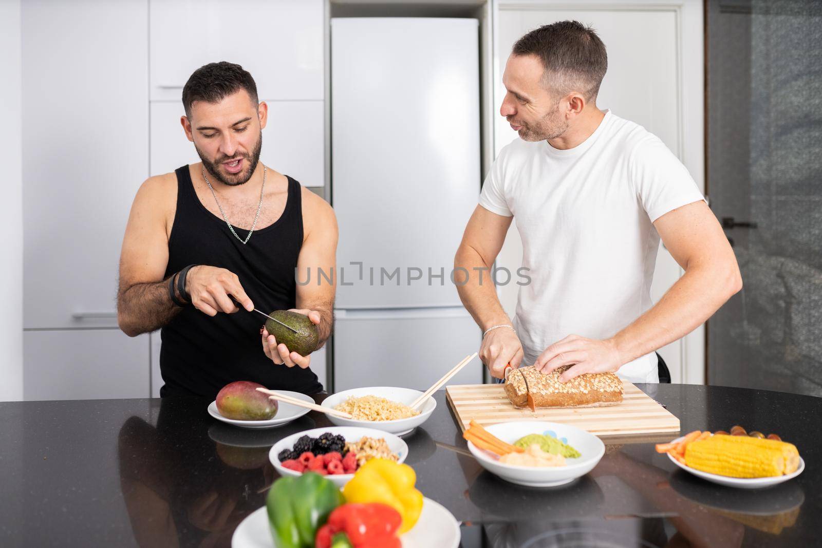 Gay couple cooking healthy vegan food together at home. Homosexual relationship concept.