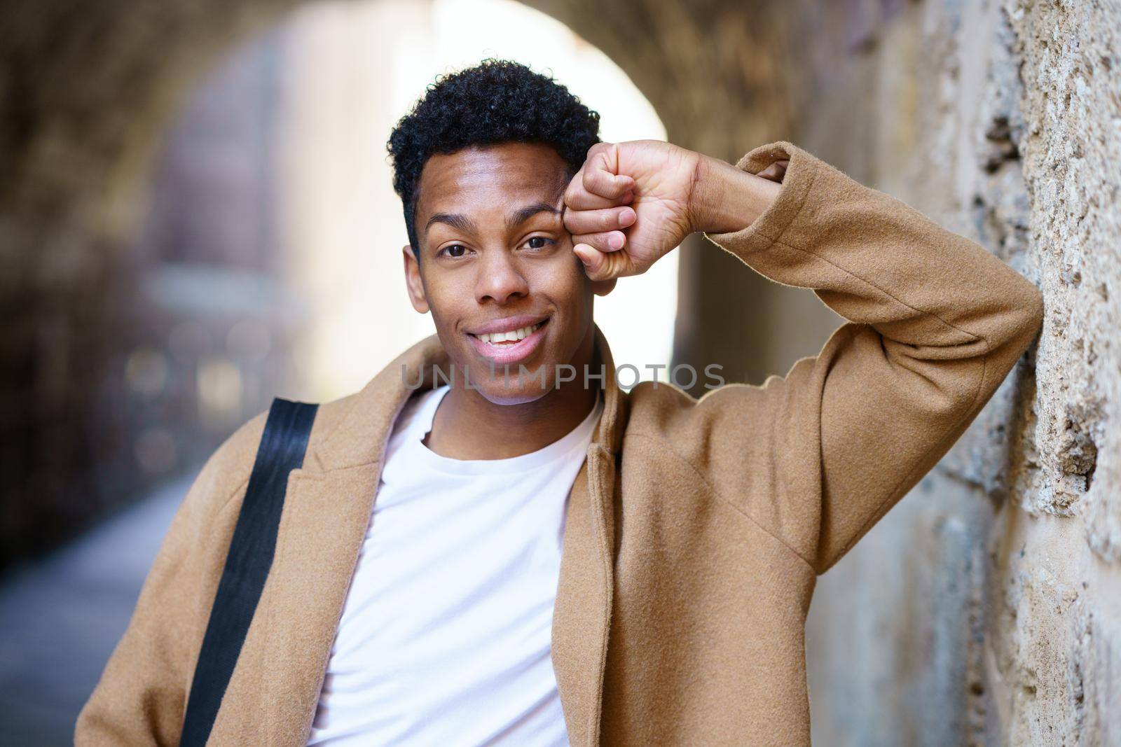 Young black man looking at camera outdoors. Cuban student in urban background.