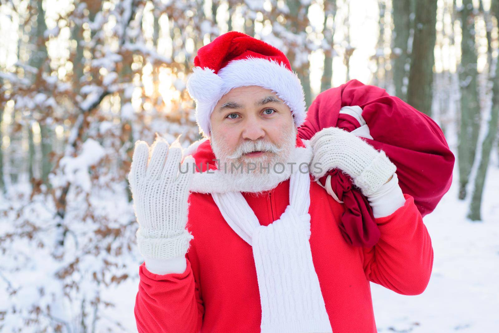 Santa in the winter field. Santa Claus on Christmas Eve is carrying presents to children in a bag. Postcard, greeting card