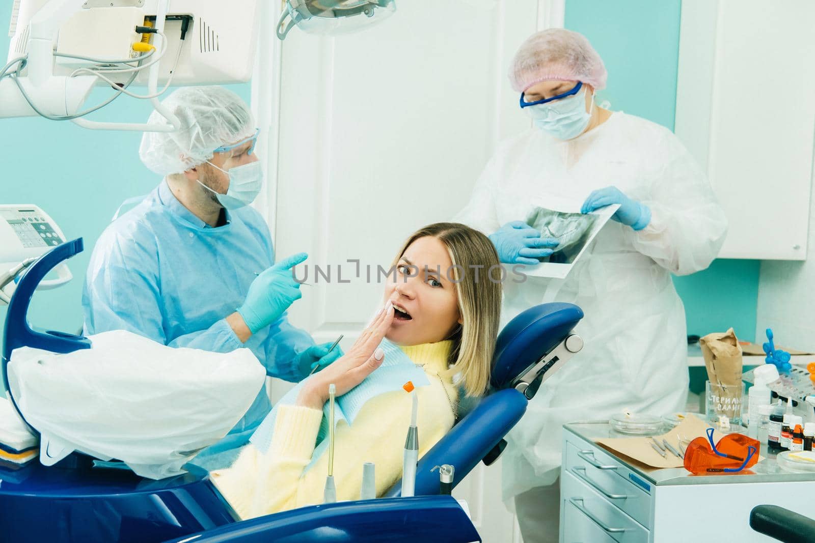 The dentist explains the details of the X-ray to his colleague, the patient is surprised by what is happening.