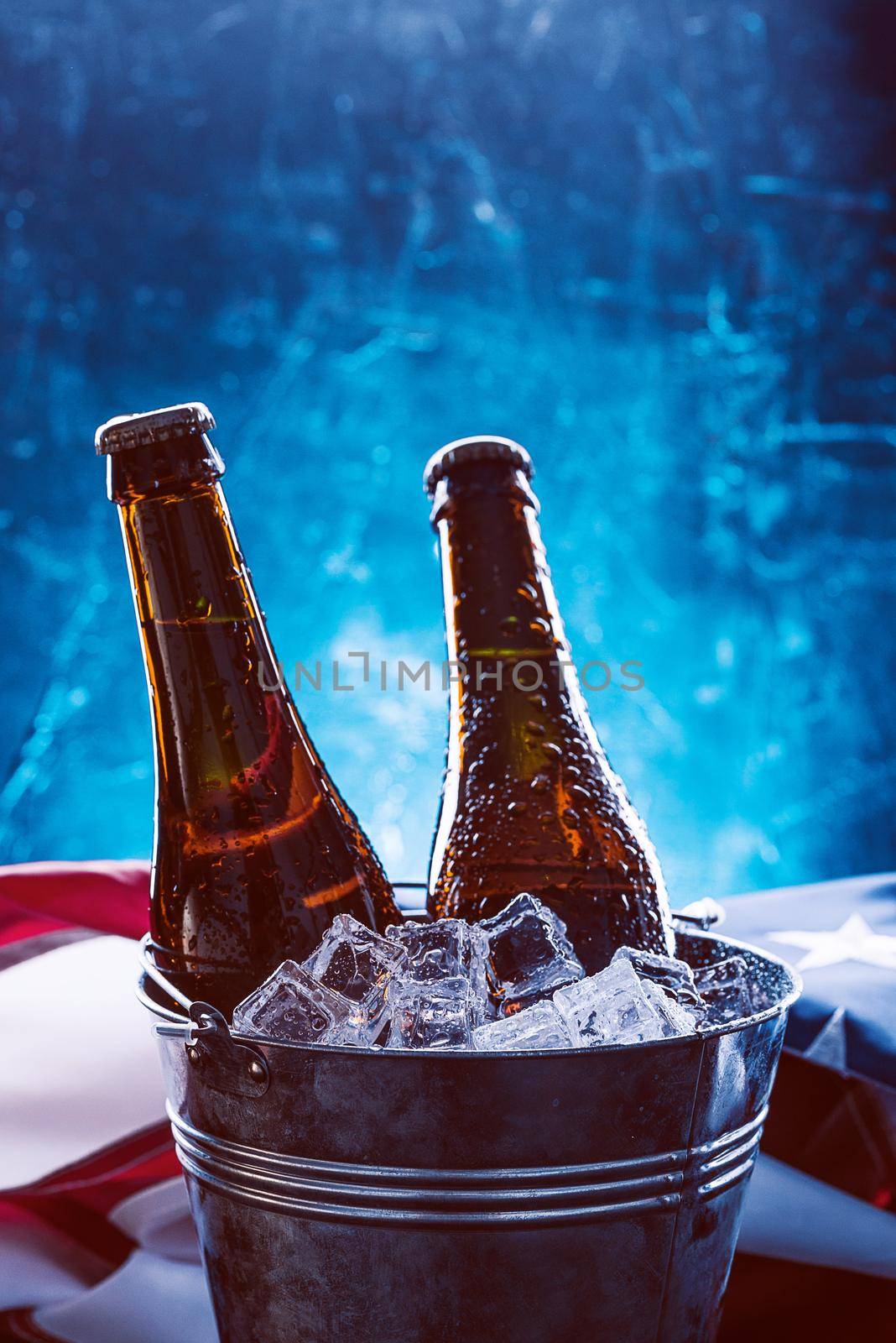 two bottles of beer in an ice bucket with the American flag lying nearby. Independence Day celebration concept by vvmich