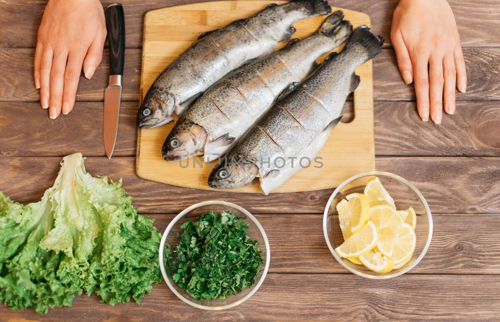 Woman will cook fish on wooden table. by alexAleksei