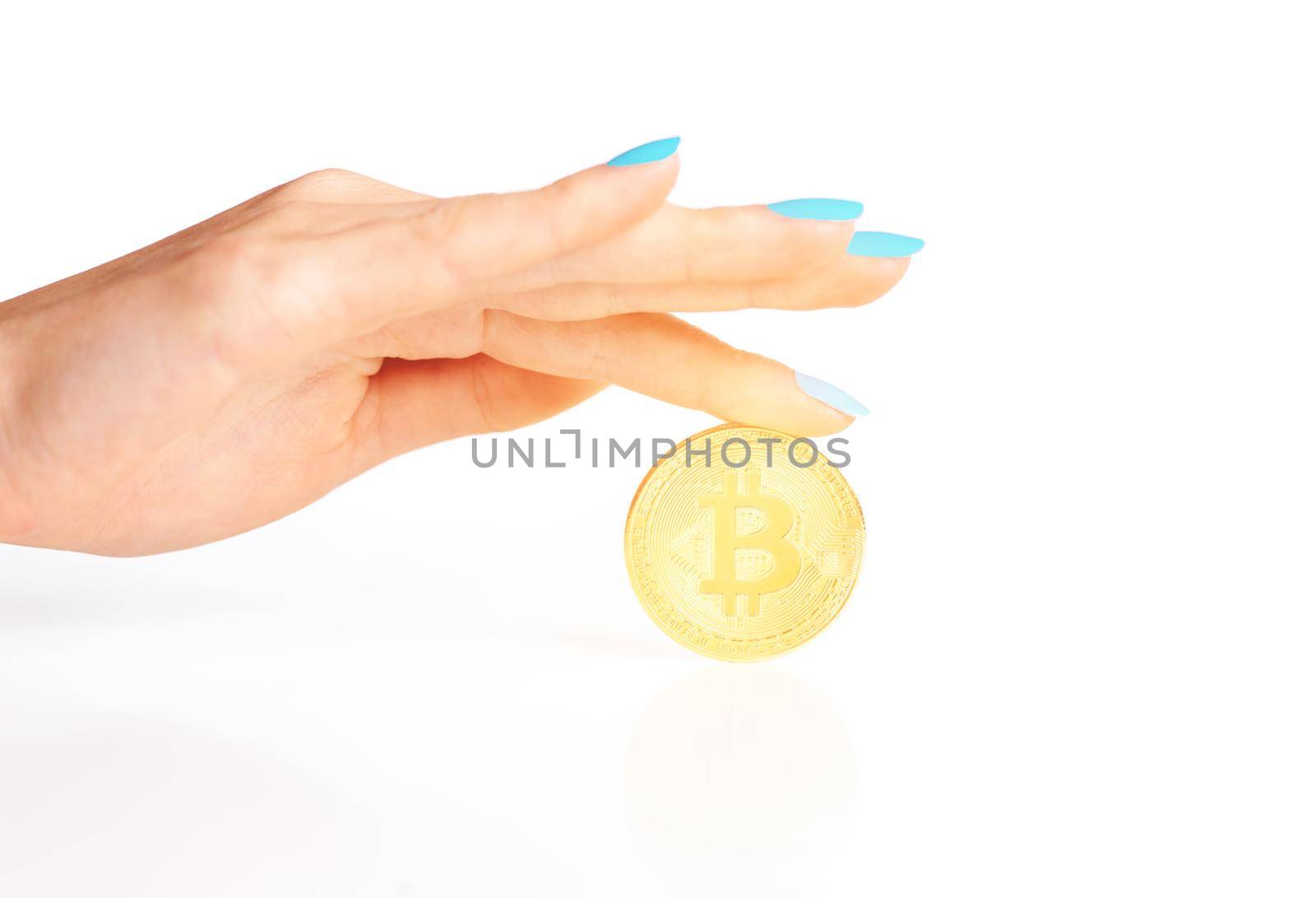 Female hand with glowing gold coin bitcoin on a white background, symbol of crypto currency.
