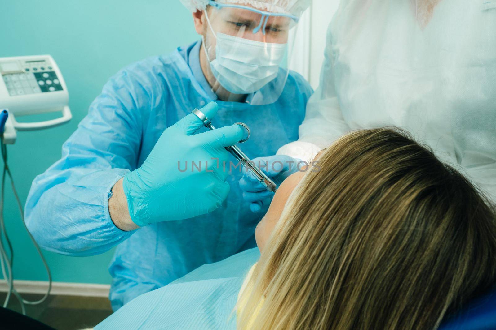 a dentist in a protective mask colitis painkillers in the dental office with an assistant.