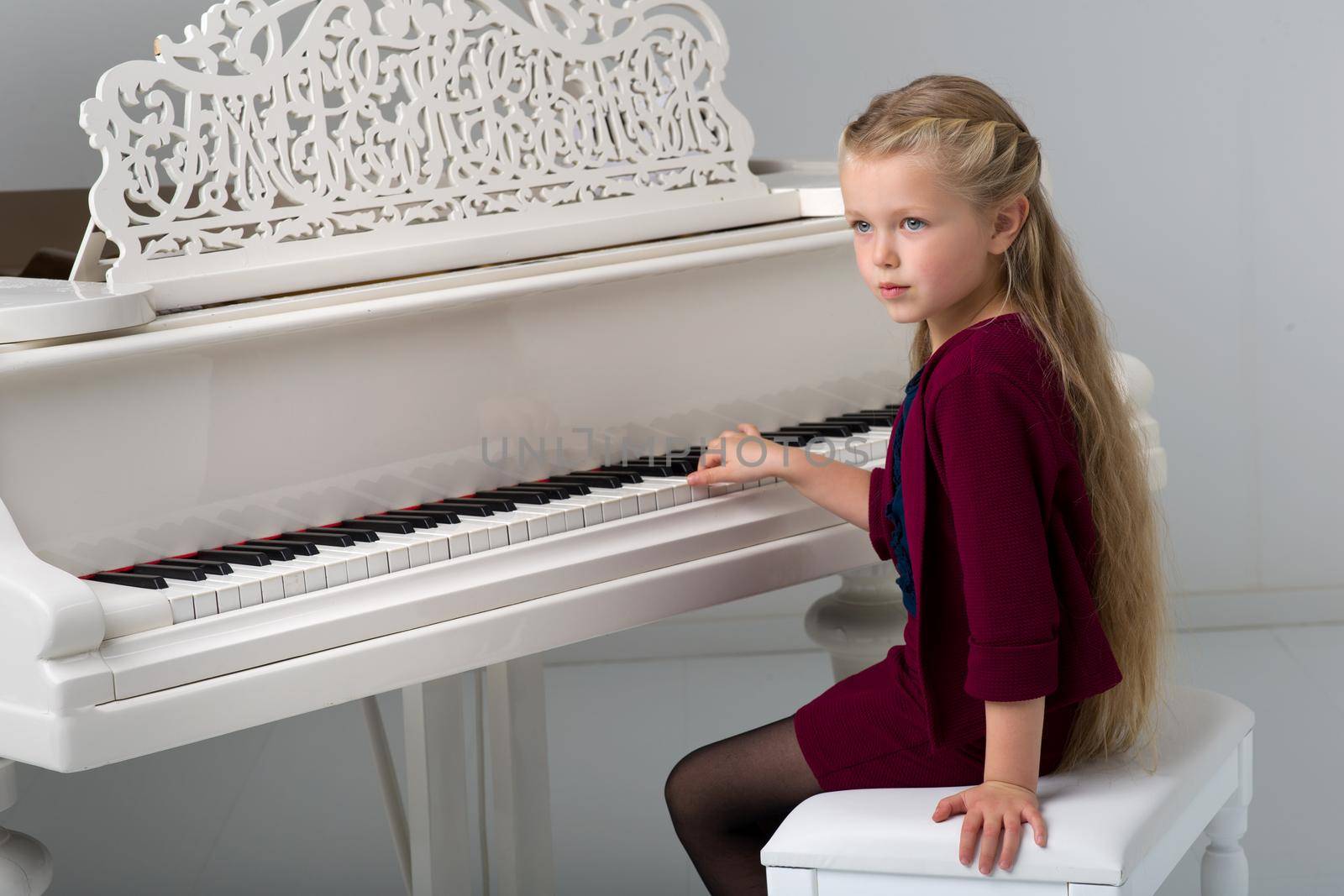 Smiling girl playing grand piano by kolesnikov_studio