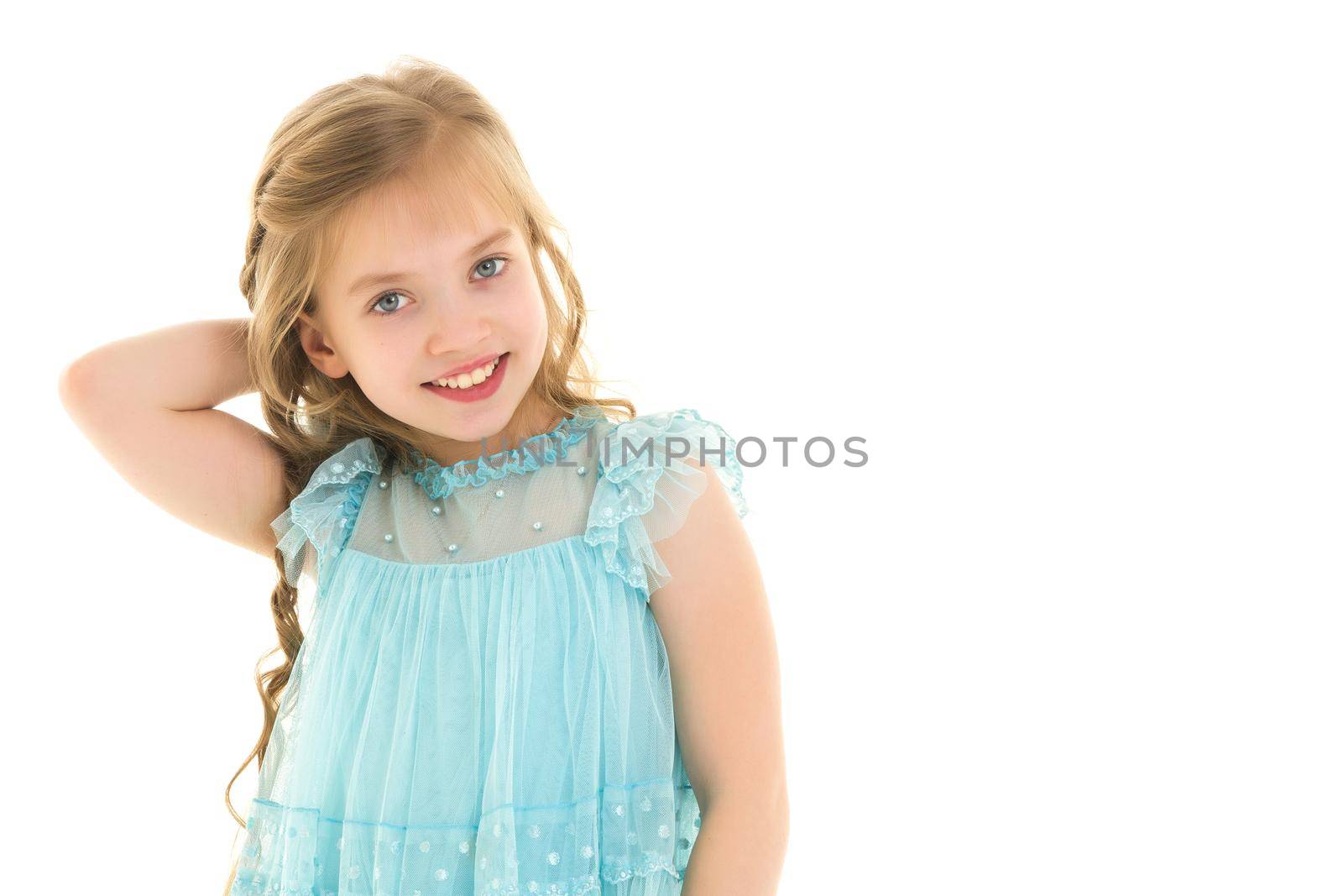 A charming little school girl corrects her long silky hair with her hands. The concept of style and fashion, happy people. Isolated on white background.