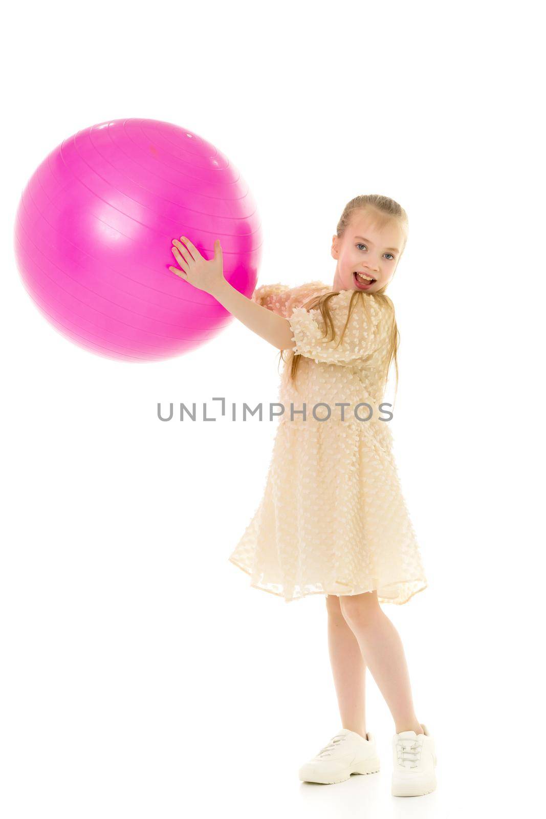 Beautiful little girl is playing with a big ball for fitness. Sports concept, happy childhood. Isolated over white background.
