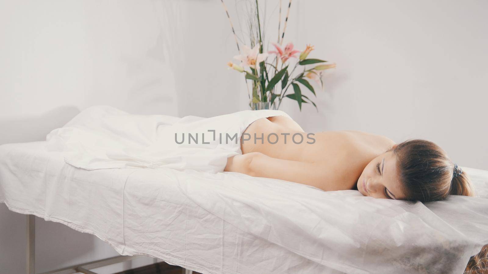 Young female relaxing in spa salon before oil sesame massage, close up