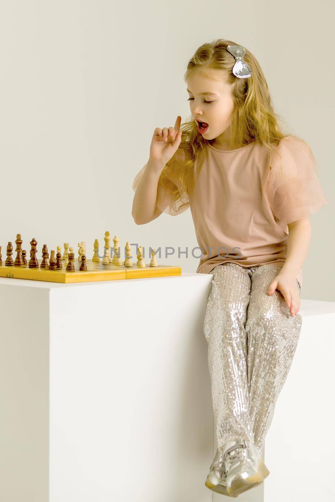 A little girl is playing chess. The concept of creative education of a child, training of thinking.