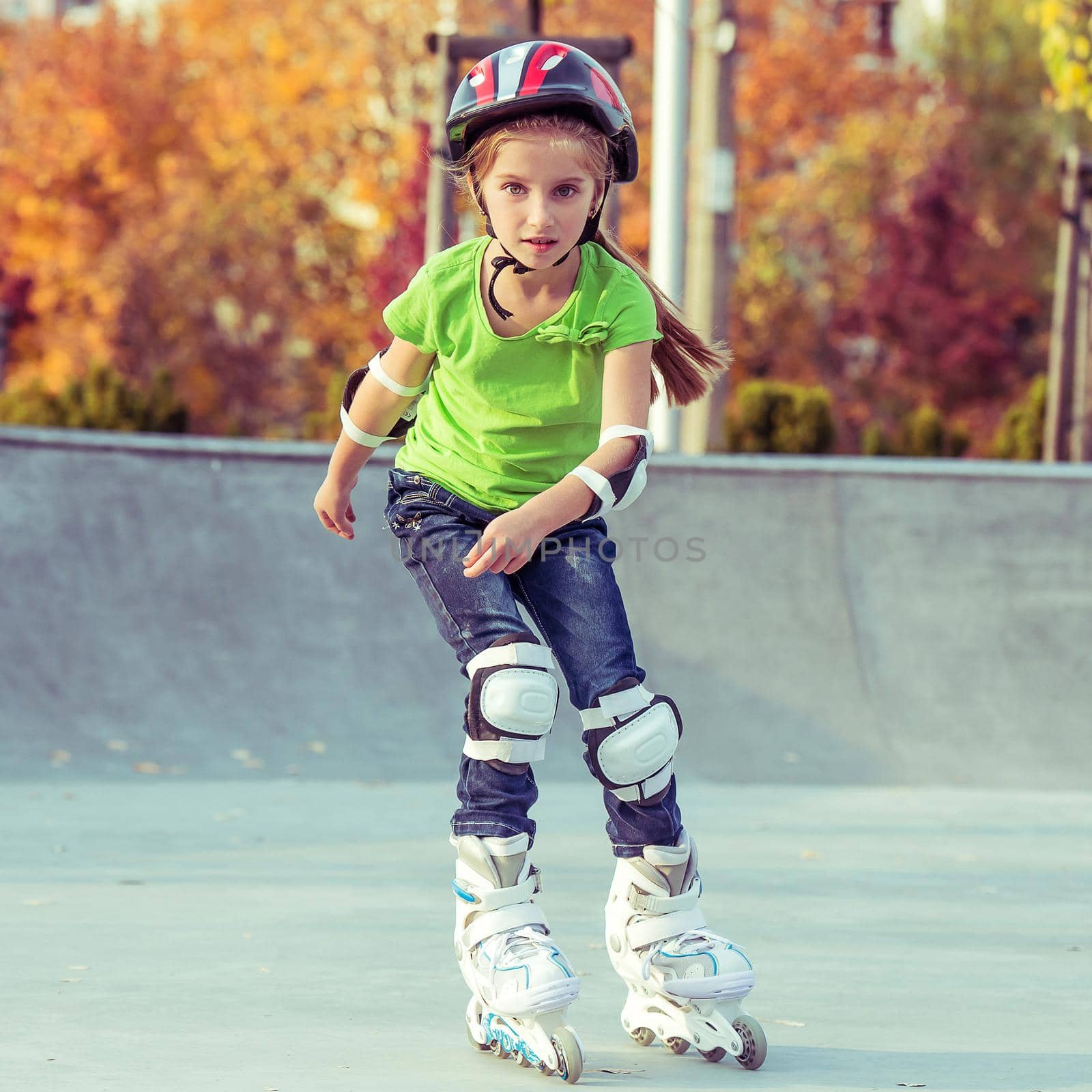 Little girl on roller skates in helmet at a park