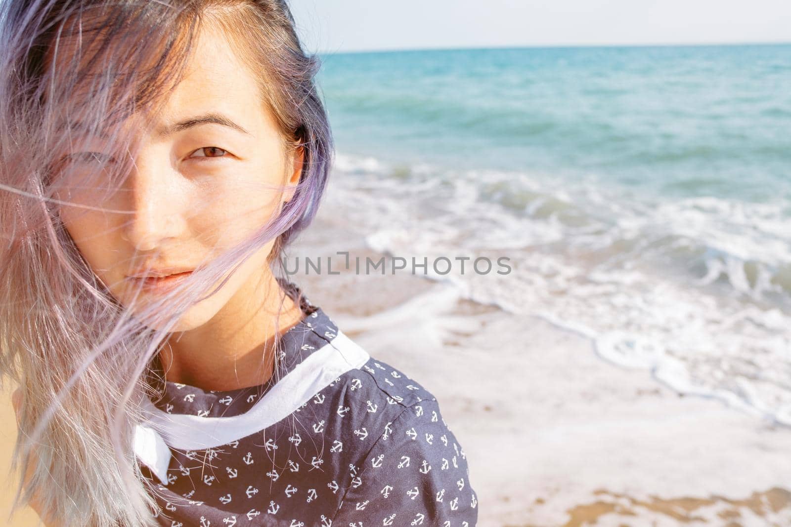 Portrait of young woman on background of sea, looking at camera.