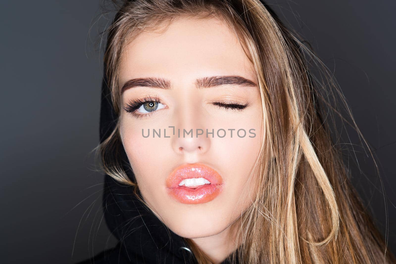 Girl funny face close up. Woman Winking. Beauty fashion portrait. Smiling young woman wink up. by Tverdokhlib
