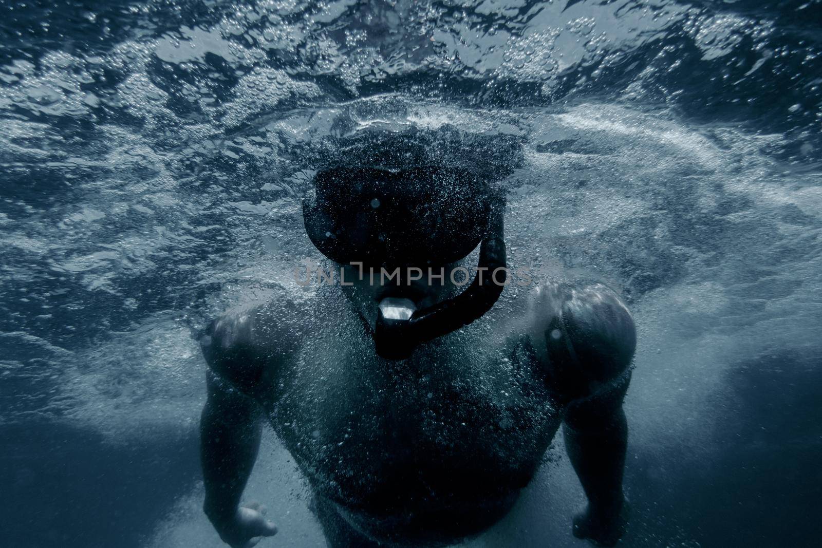 Sporty young man freediver snorkeling underwater surface.