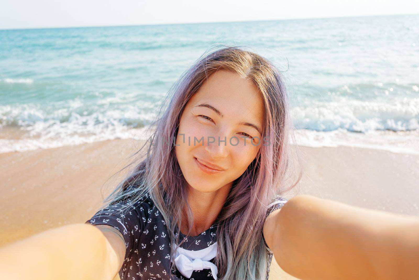 Smiling young woman taking selfie on background of sea on summer vacations, point of view.