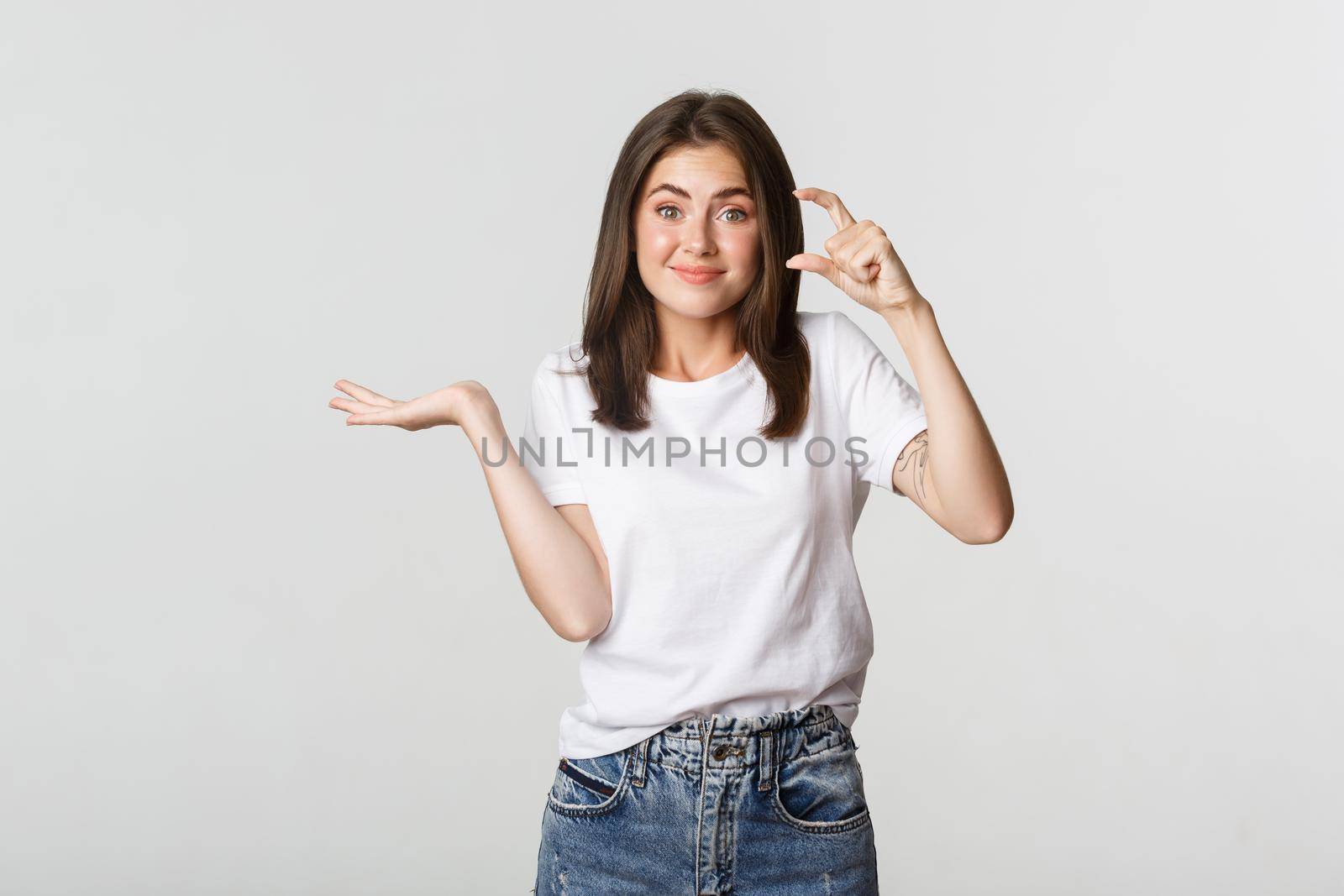 Skeptical and unamused brunette girl showing something too small, tiny object.