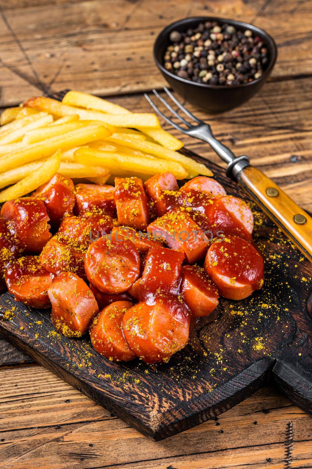 Currywurst Sausages street food served French fries on a wooden board. wooden background. Top view.