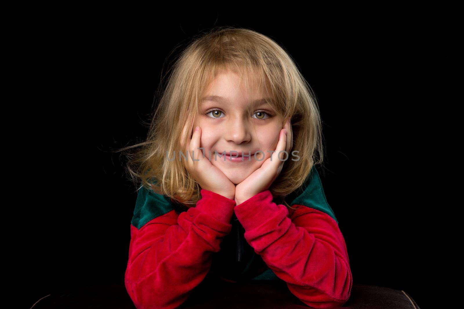 Close up view of a cute smiling little girl posing on black background. by kolesnikov_studio