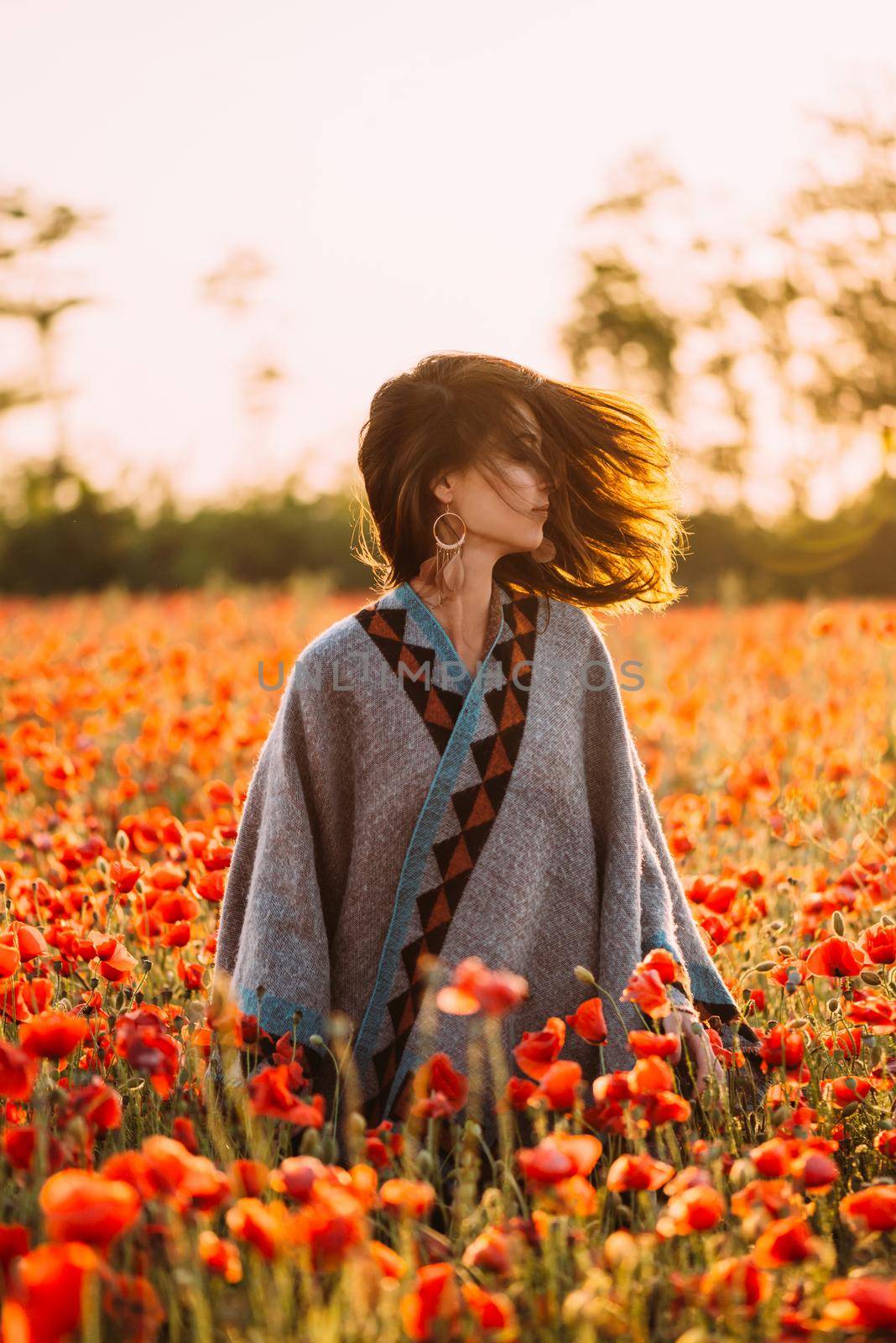 Boho stylish woman walking in red poppies meadow. by alexAleksei