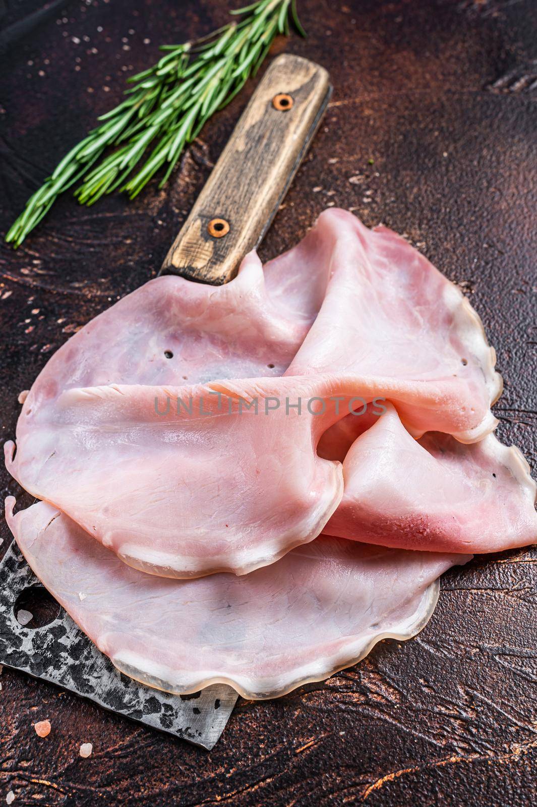 Sliced Ham Prosciutto on a butcher cleaver. Dark background. Top view.