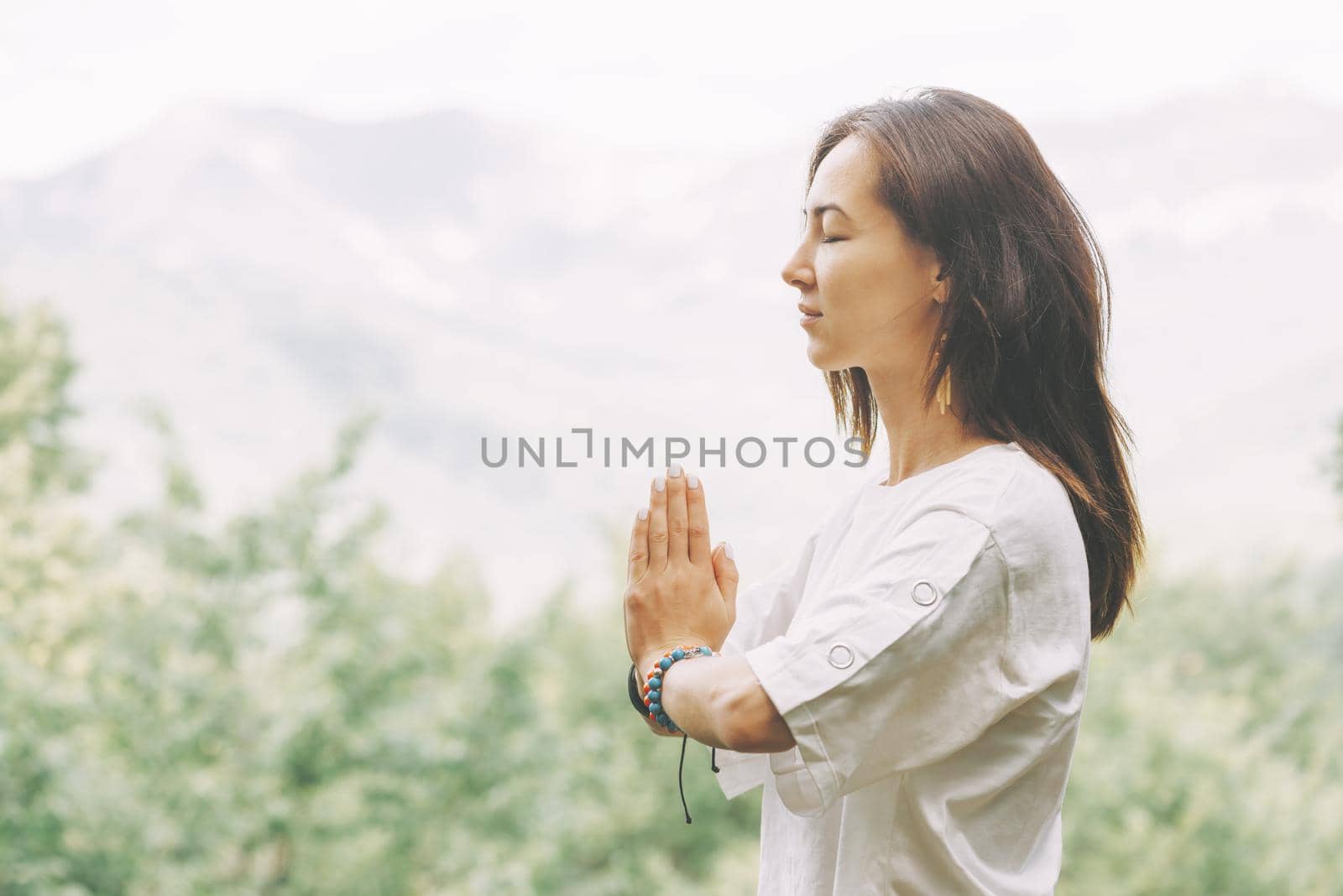 Young woman practicing yoga and meditating with closed eyes in summer outdoor.