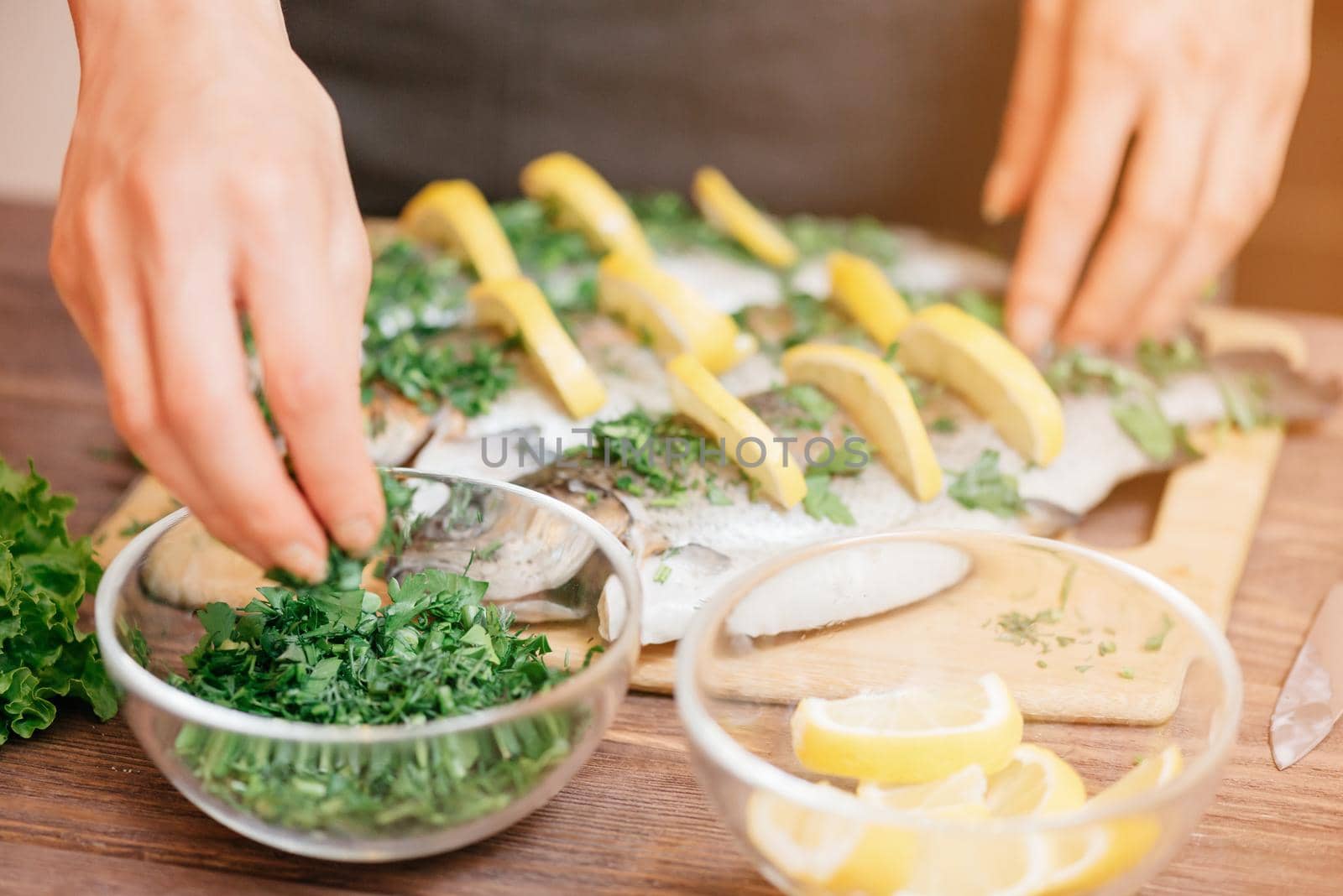 Female hands preparing fish with lemons and greenery. by alexAleksei