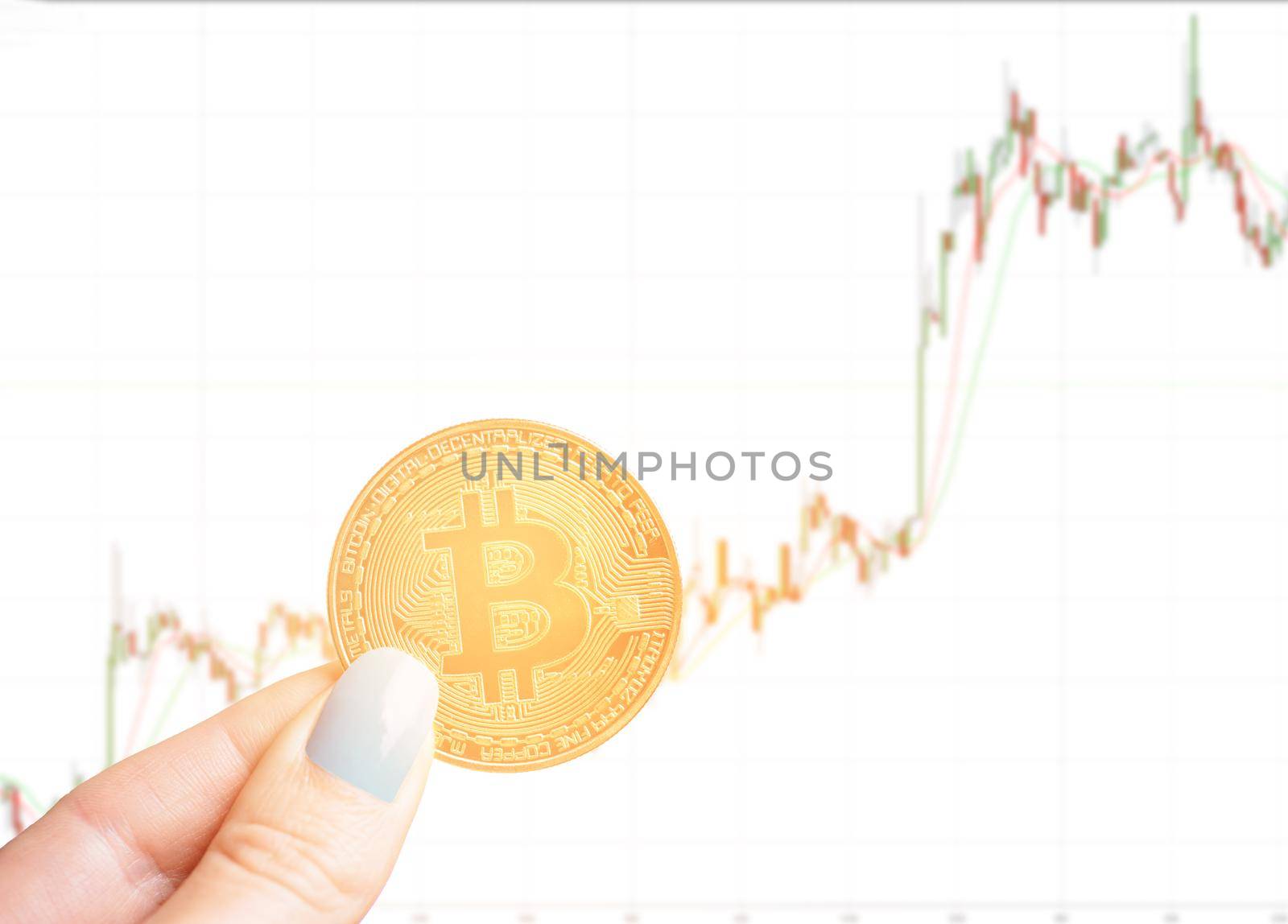 Woman’s hand holding gold coin bitcoin on background of growth diagram.