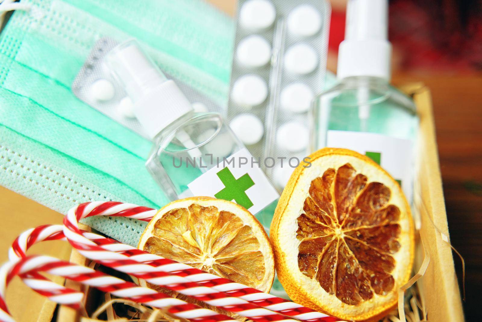 Gift box with antiseptics, pills, lollipops, medical masks and dried oranges. New Year's Eve during pandemic. Holidays in quarantine. Christmas surprise.