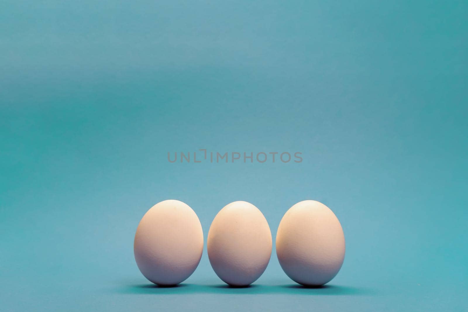Three white eggs on light blue background, minimal Easter concept, enough space for text.
