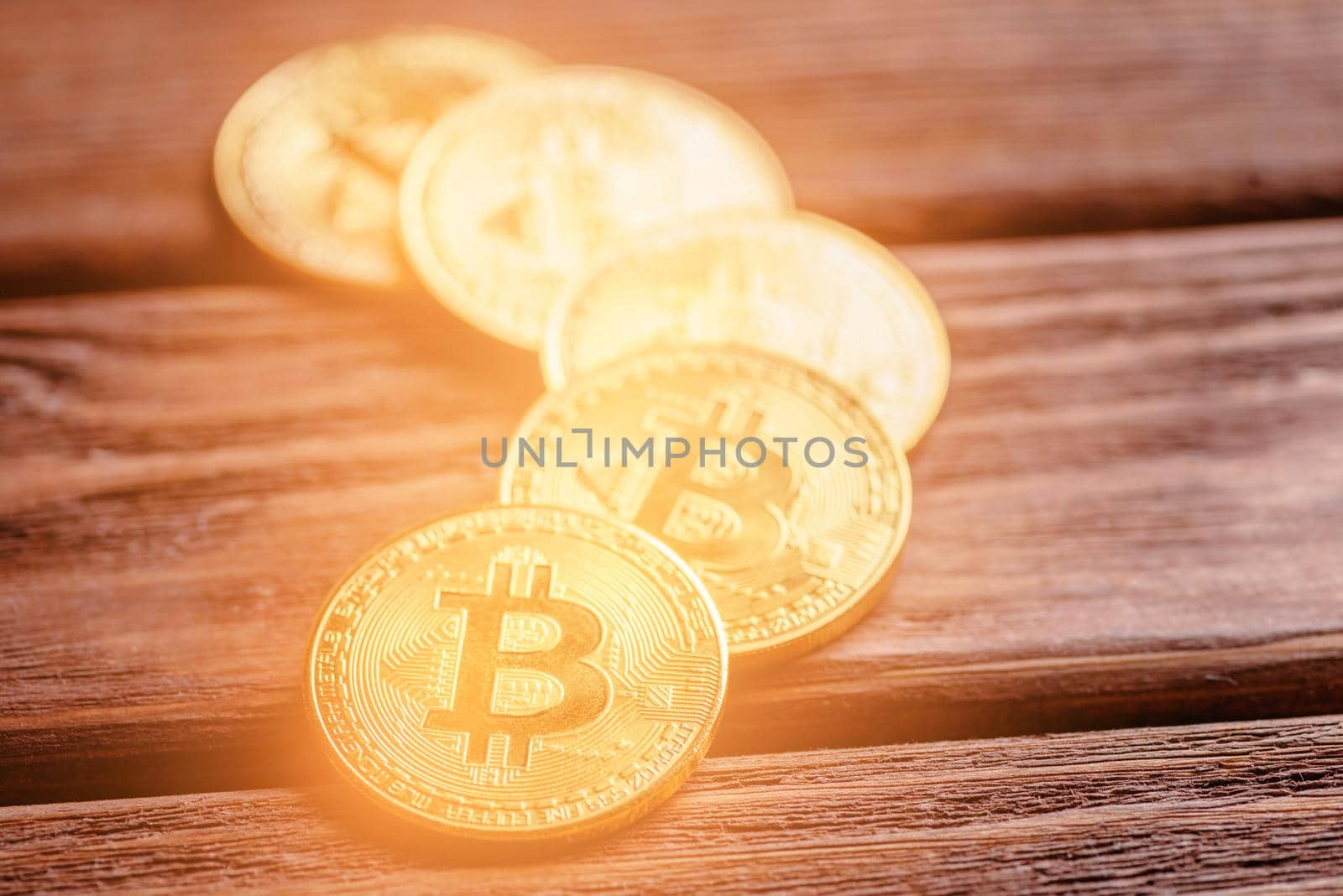 Many glowing gold bitcoins on a wooden table, close-up. Symbol of crypto currency and virtual money.