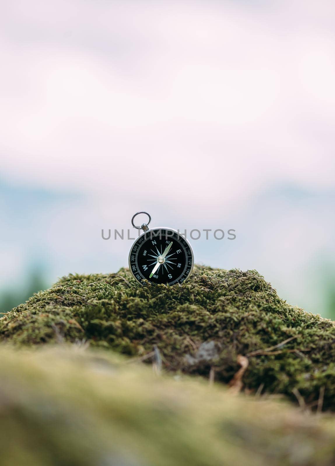 Magnetic compass on cliff covered with moss outdoor. Copy-space in upper part of image.