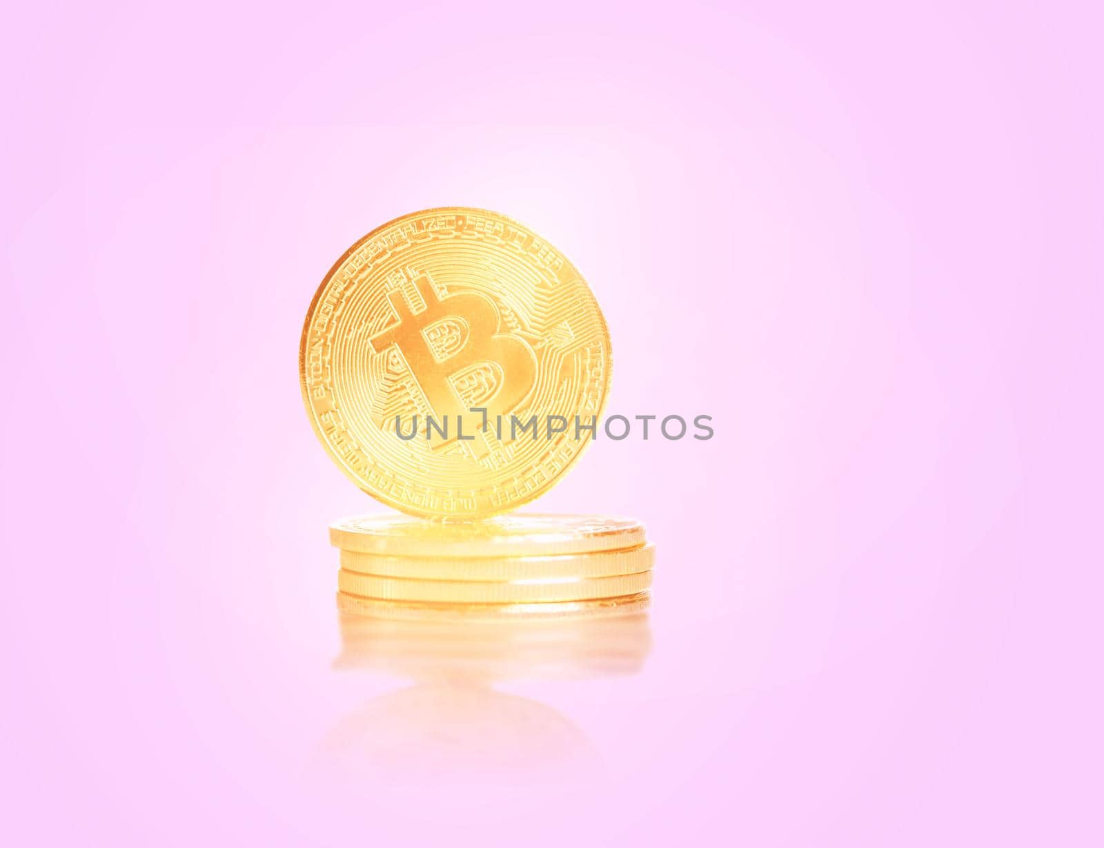 Stack of glowing gold coins bitcoins on a pink background.