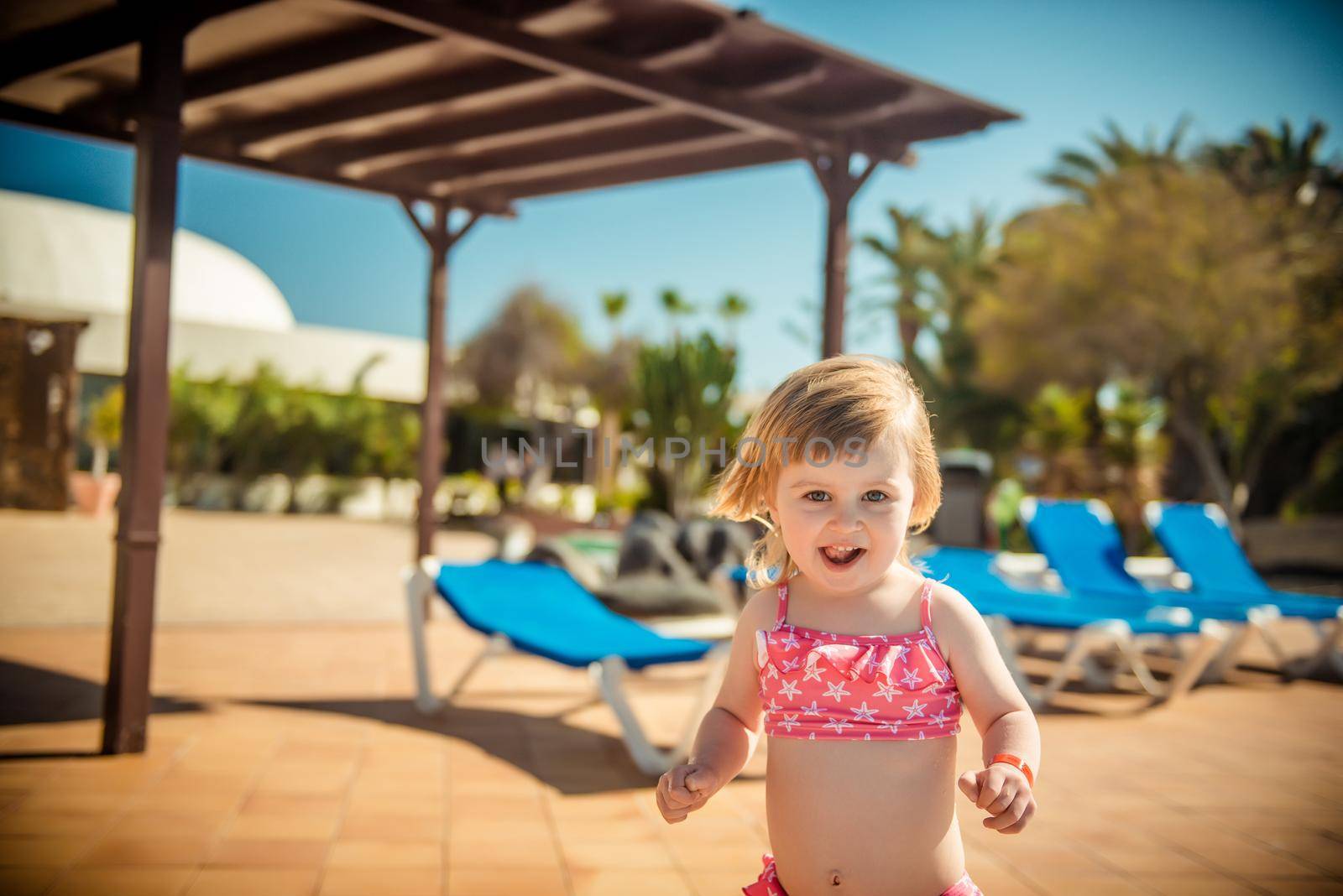 little cheerful girl running around the pool