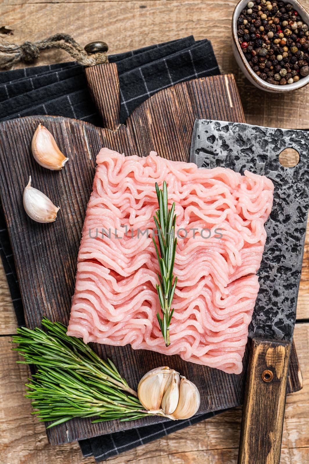 Raw minced chicken and turkey meat on wooden chopping board with butcher cleaver. wooden background. Top view.