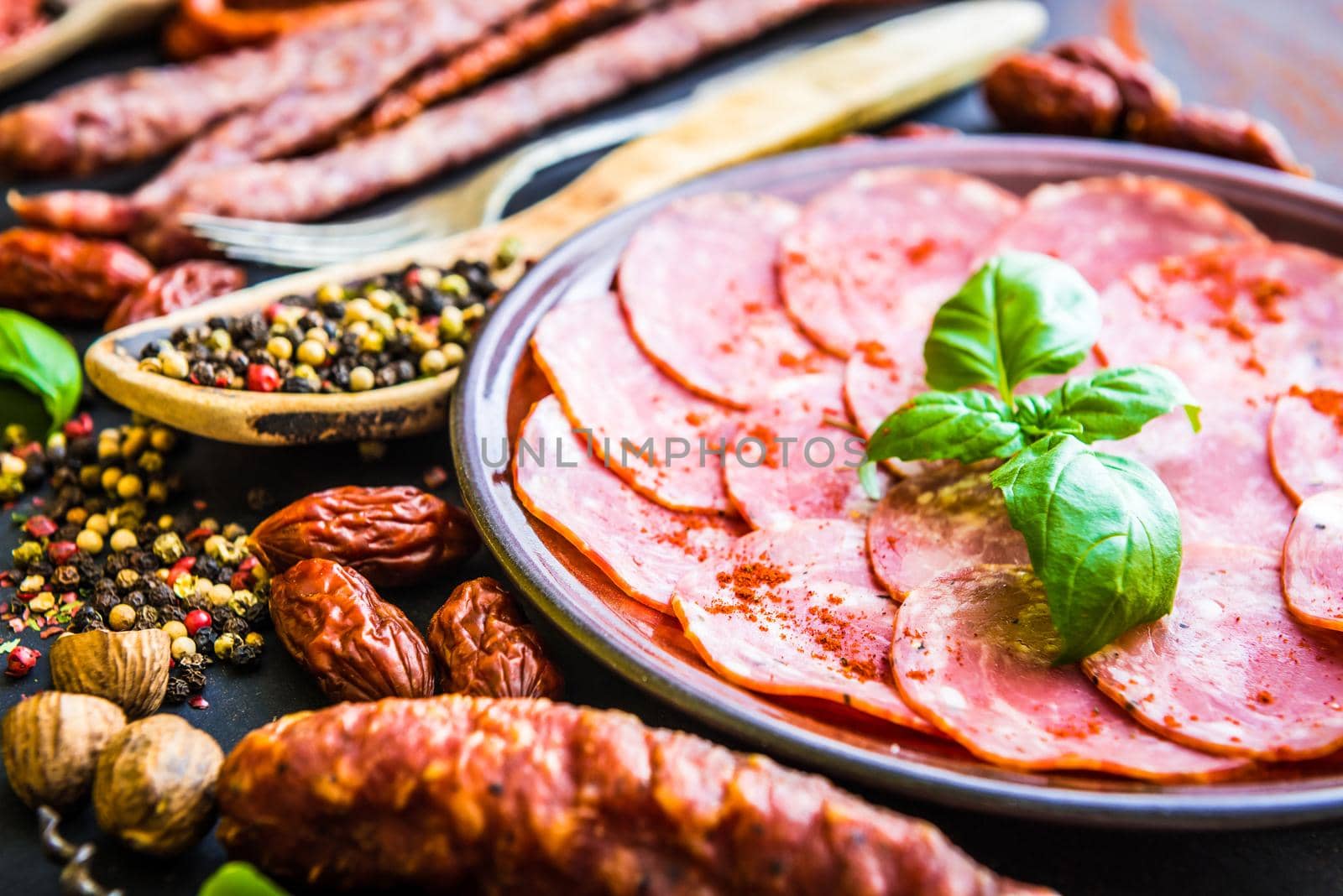 various sausages with spices on black table