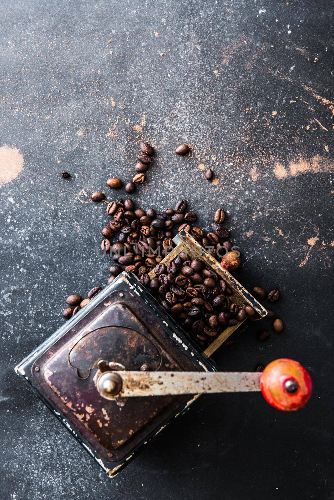 Old coffee grinder with coffee beans inside on black table