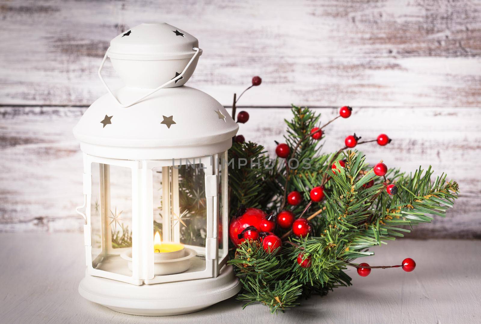 Cristmas lantern with fir and berries over shabby wooden background