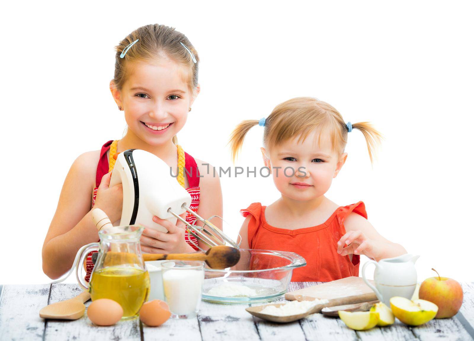 two little smiling sisters cooking isolated on a white background