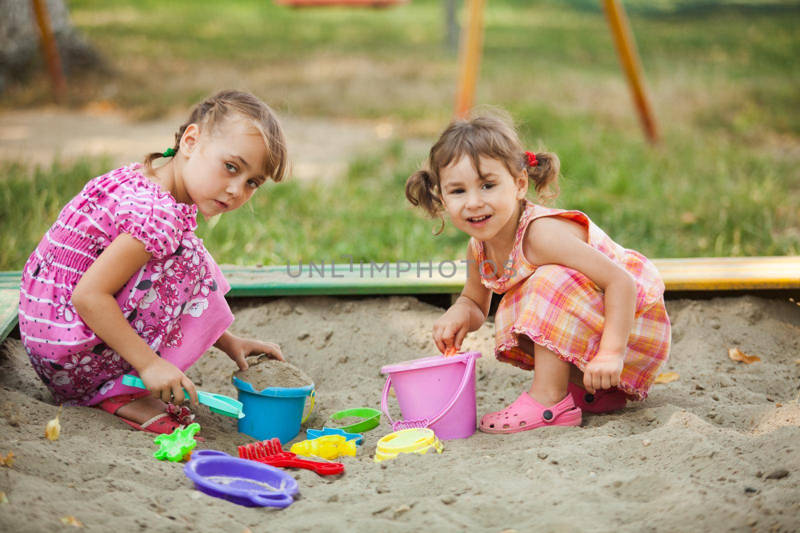 Two girls play in the sandbox at the playground